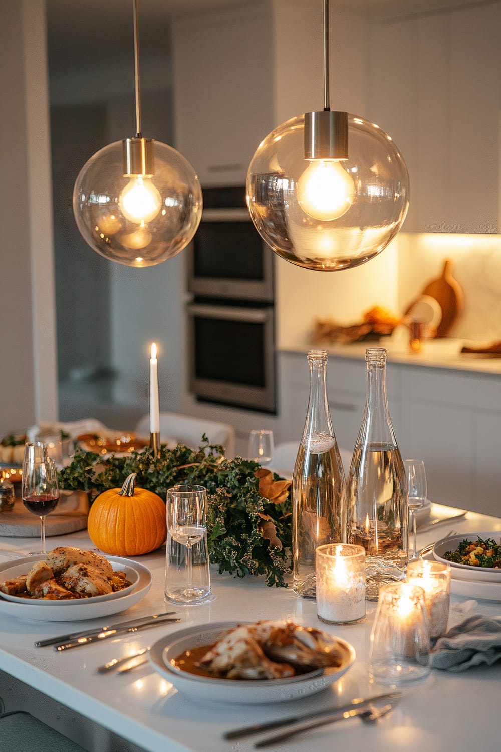 A modern kitchen island set for Friendsgiving, with plates of butternut squash soup, roasted turkey legs, and kale salad, accompanied by elegant glass carafes of mulled wine and sparkling water. The white kitchen island doubles as a dining table, adorned with a minimalist metallic centerpiece featuring candles and seasonal greenery. Two large pendant lights illuminate the clean kitchen backdrop.