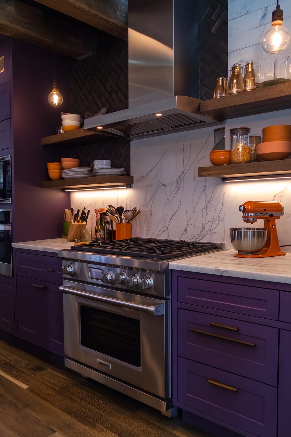 An overhead view of a farmhouse kitchen with deep plum cabinets, light grey marble countertops, and orange kitchenware. The kitchen features stainless steel appliances, including an oven and dishwasher, wooden shelves with utensils and decor, warm Edison bulb lighting, and dark hardwood floors.