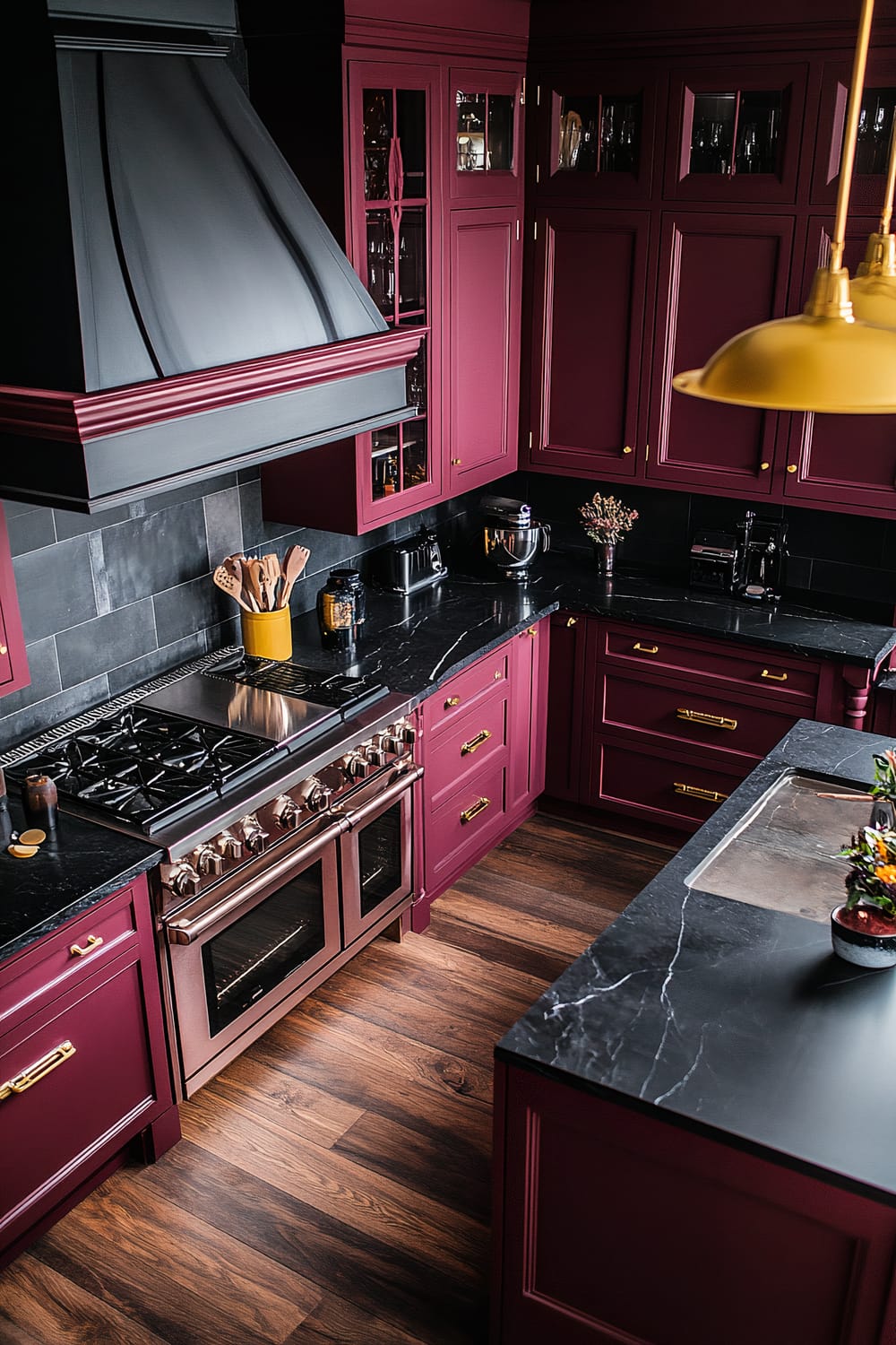 A top-down perspective of a moody farmhouse kitchen featuring rich burgundy cabinets, glossy black granite countertops, bright yellow pendant lights, and dark wood floors. The kitchen includes a Café espresso maker on a stylish marble countertop, a gas range with a unique hood design, and a dishwasher behind open shelving.