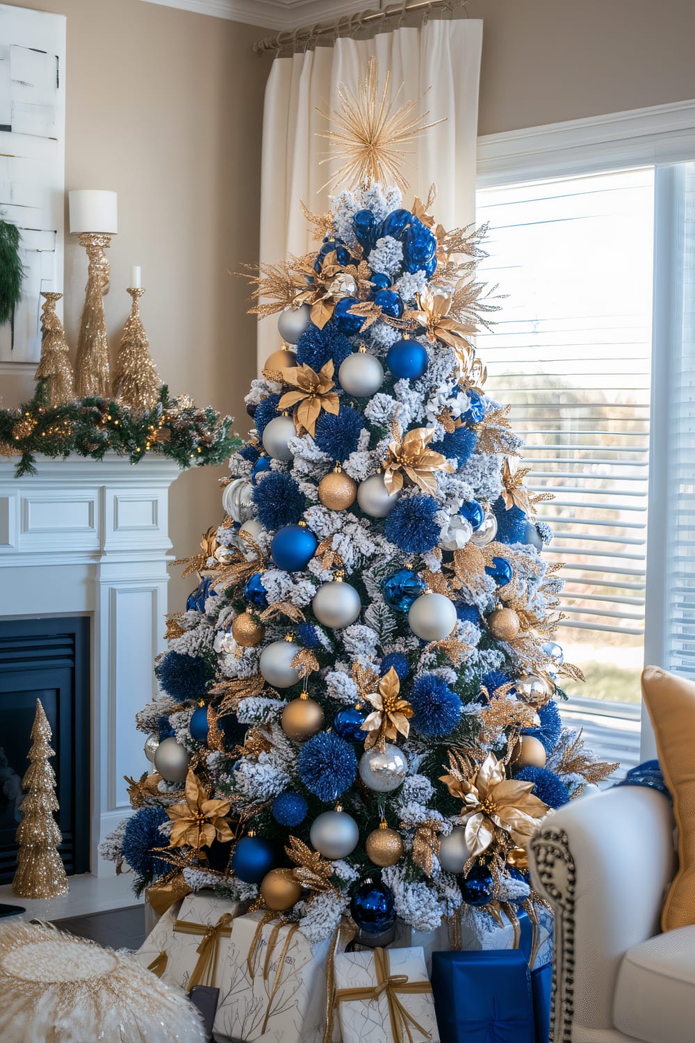 A lavishly decorated Christmas tree adorned with blue, gold, and silver ornaments. The tree is flocked with faux snow and topped with a large, radiant starburst. Surrounding the base are wrapped gifts in coordinating blue and white paper with golden bows. The tree is set in a bright, elegant living room next to a fireplace adorned with gold and green holiday decorations.