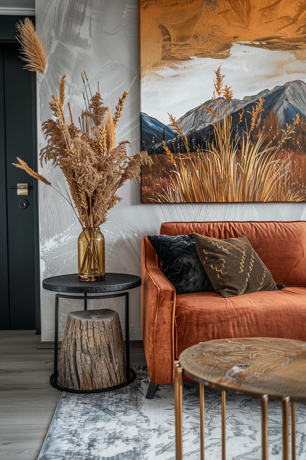 An interior scene featuring an orange velvet sofa with dark cushions, a black round side table holding a vase with dried flowers, a tree stump under the table, and a large abstract painting with golden and earthy tones on the wall.