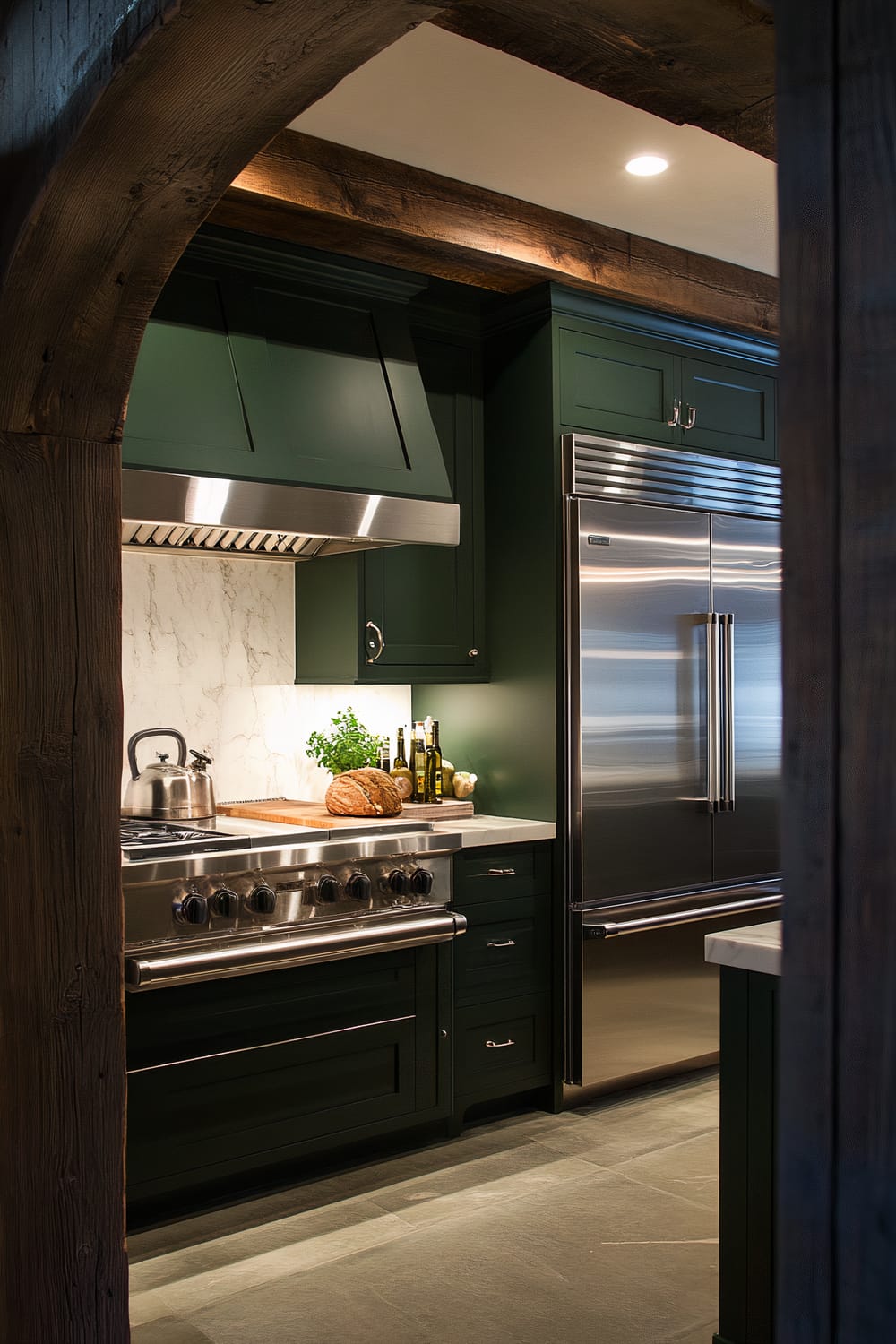 An atmospheric farmhouse kitchen with forest green cabinets, white marble countertops, and stainless steel appliances, viewed through an arch doorway.