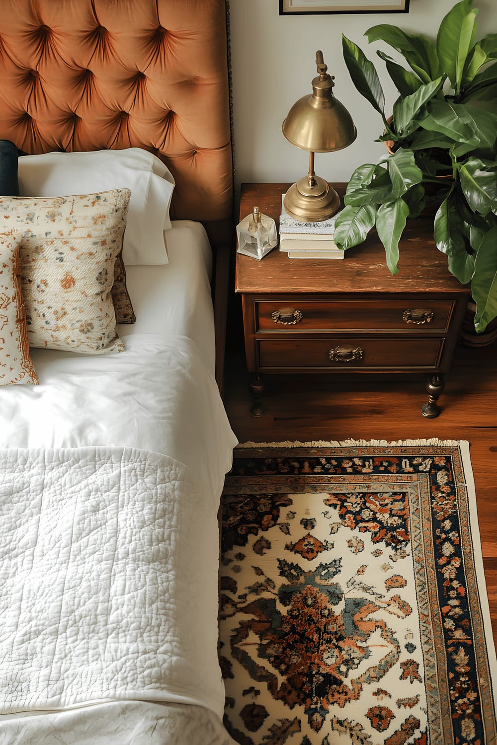 A top-down view of a vintage-inspired bedroom featuring a bed with a tufted headboard, a reclaimed wood nightstand adorned with a brass lamp, and an intricately patterned area rug. A draft of soft natural light imbues the room with a warm and timeless charm.