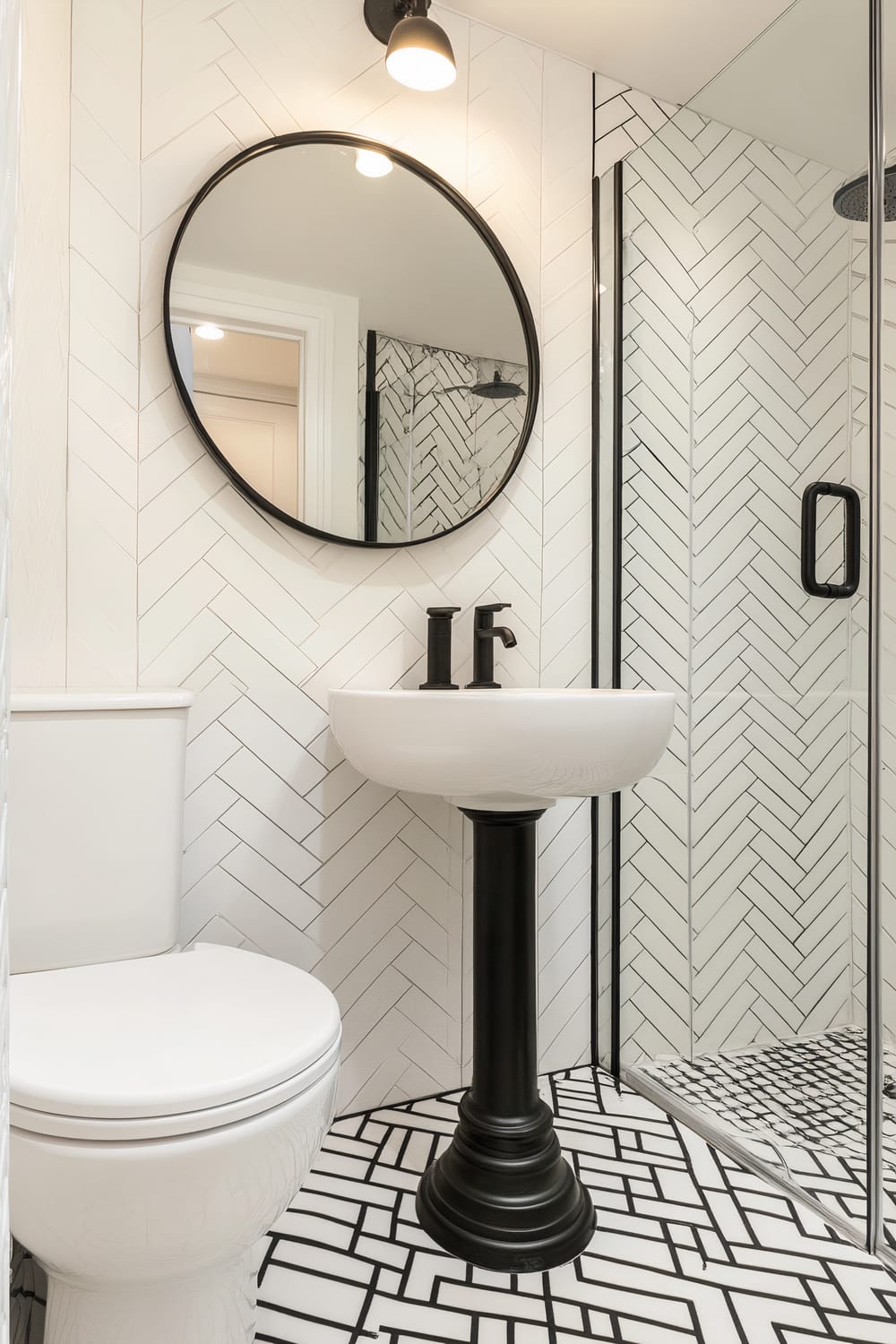 A modern bathroom features a round mirror with a black frame above a pedestal sink with black fixtures. The walls are adorned with white tiles arranged in a herringbone pattern. The toilet, positioned next to the sink, is white. The flooring consists of white tiles with black geometric patterns, complementing the design aesthetics. There is a glass door leading to a shower area which also features the same herringbone tile pattern and a black showerhead.