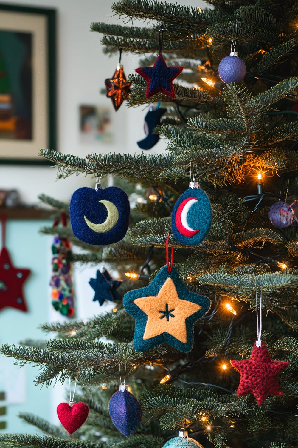 A close-up of a Christmas tree decorated with various felt ornaments in different shapes and colors. The ornaments include stars, crescent moons, and balls in shades of blue, red, yellow, and purple. The tree is also adorned with tiny lights that add a warm glow.