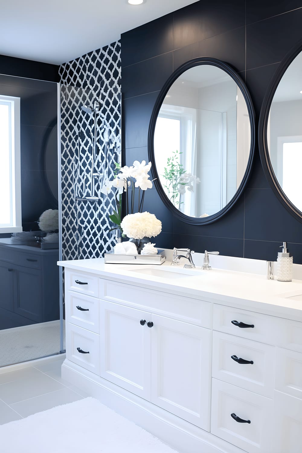 A chic black and white bathroom featuring bold geometric black tiles on the floor and lower half of the walls, a sleek white vanity with a stylish basin sink, a frameless glass shower, and a large oval mirror with a black and white geometric pattern on its frame. Bright, focused lighting illuminates the room, highlighting the modern and minimalist design. A white towel hangs neatly on a rack, and a simple vase with a single monochrome flower stands on the vanity.