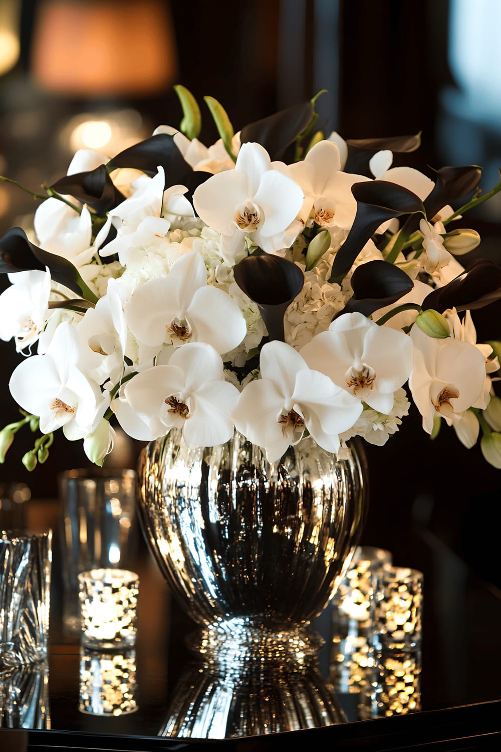 A glamorous arrangement of white orchids and black calla lilies in a mirrored vase placed on a glossy black table. The table is adorned with Art Deco accents including metallic gold decor pieces and geometric patterns. Ambient lighting subtly emphasizes the sophistication of the scene.