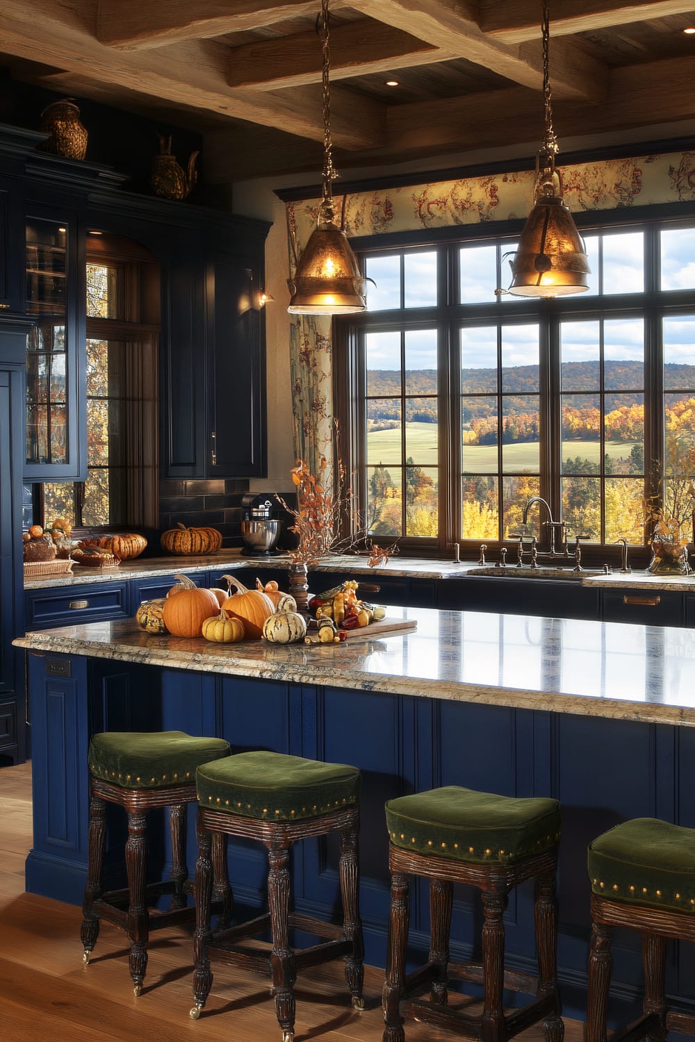 A sophisticated kitchen interior featuring deep navy blue cabinetry with a rustic wooden ceiling. The room includes large black-framed windows providing a scenic view of an autumnal landscape. A kitchen island with a polished marble countertop is adorned with an assortment of decorative pumpkins and gourds. Above the island are two vintage-style pendant lights, and four green, upholstered bar stools line the island.