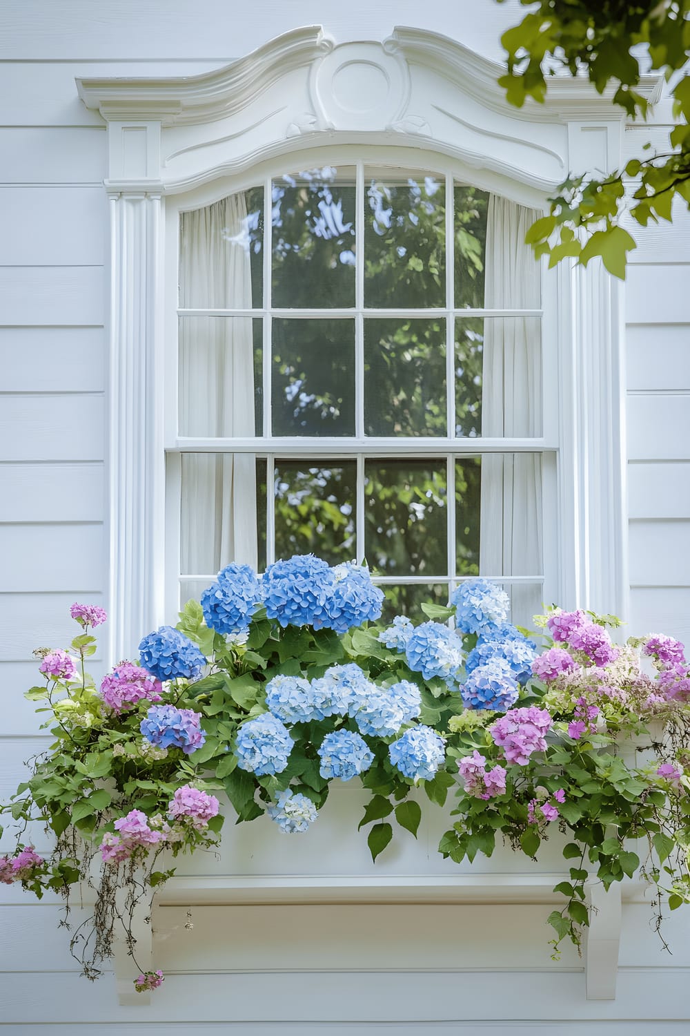 A beautiful Victorian-style home featuring white window frames, each adorned with meticulously arranged window boxes filled with flowers in shades of blue and pink, and trailing vines. The sophisticated arrangement stands out against the soft, diffused light of a cloudy spring day.