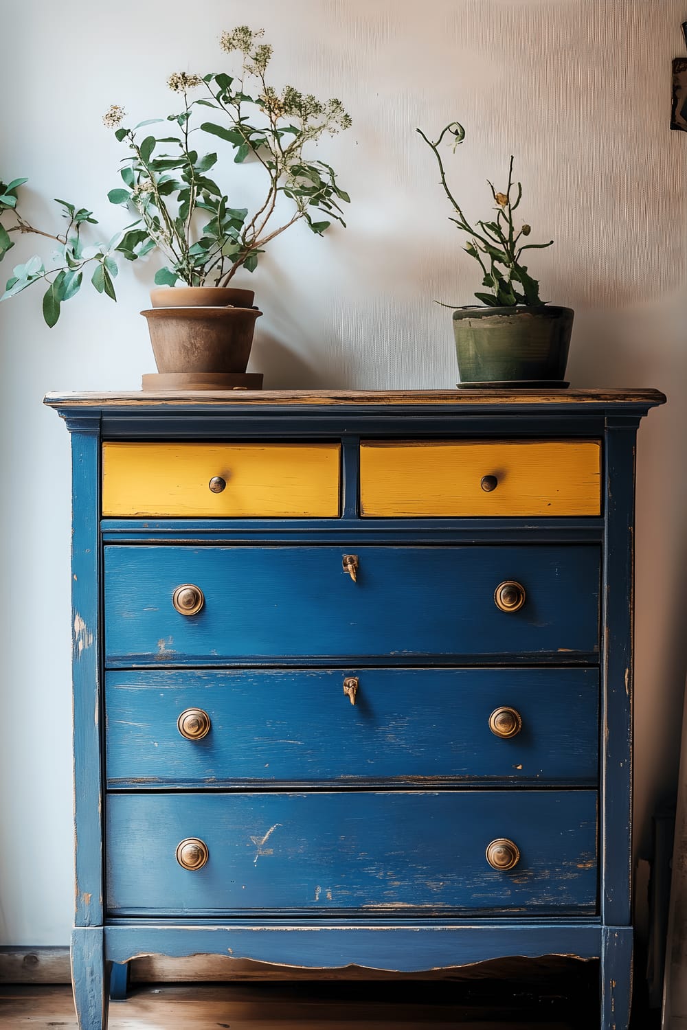 A salvaged wooden dresser painted in a vibrant cobalt blue, featuring a stunning contrast of mustard yellow interiors within the drawers, set against a soft, neutral-toned wall in the background.