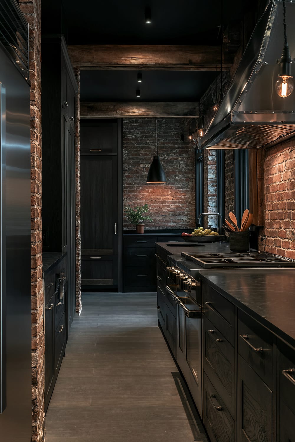 A dramatic moody farmhouse kitchen with dark cabinetry, exposed brick walls, and distressed wooden beams. It features charcoal grey cabinetry, a stainless steel refrigerator, black countertops, and an exposed brick wall. Bold dark pendant lights hang from the ceiling, contributing to the moody atmosphere.