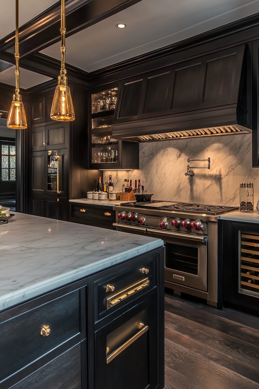 The image showcases a luxurious kitchen with a sophisticated mix of traditional and modern elements. The dark wood cabinetry contrasts beautifully with the bright, veined white marble countertops. A large kitchen island occupies the foreground, topped with the same marble and enhanced with gold hardware. Overhead, two elegant pendant lights with amber glass shades provide warm, ambient lighting. The stovetop and oven are high-end stainless steel appliances featuring red knob controls. A marble backsplash extends behind the stovetop, giving a consistent cohesive look with the countertops. The kitchen also features a built-in wine cooler, and shelves stocked with glassware and various bottles.